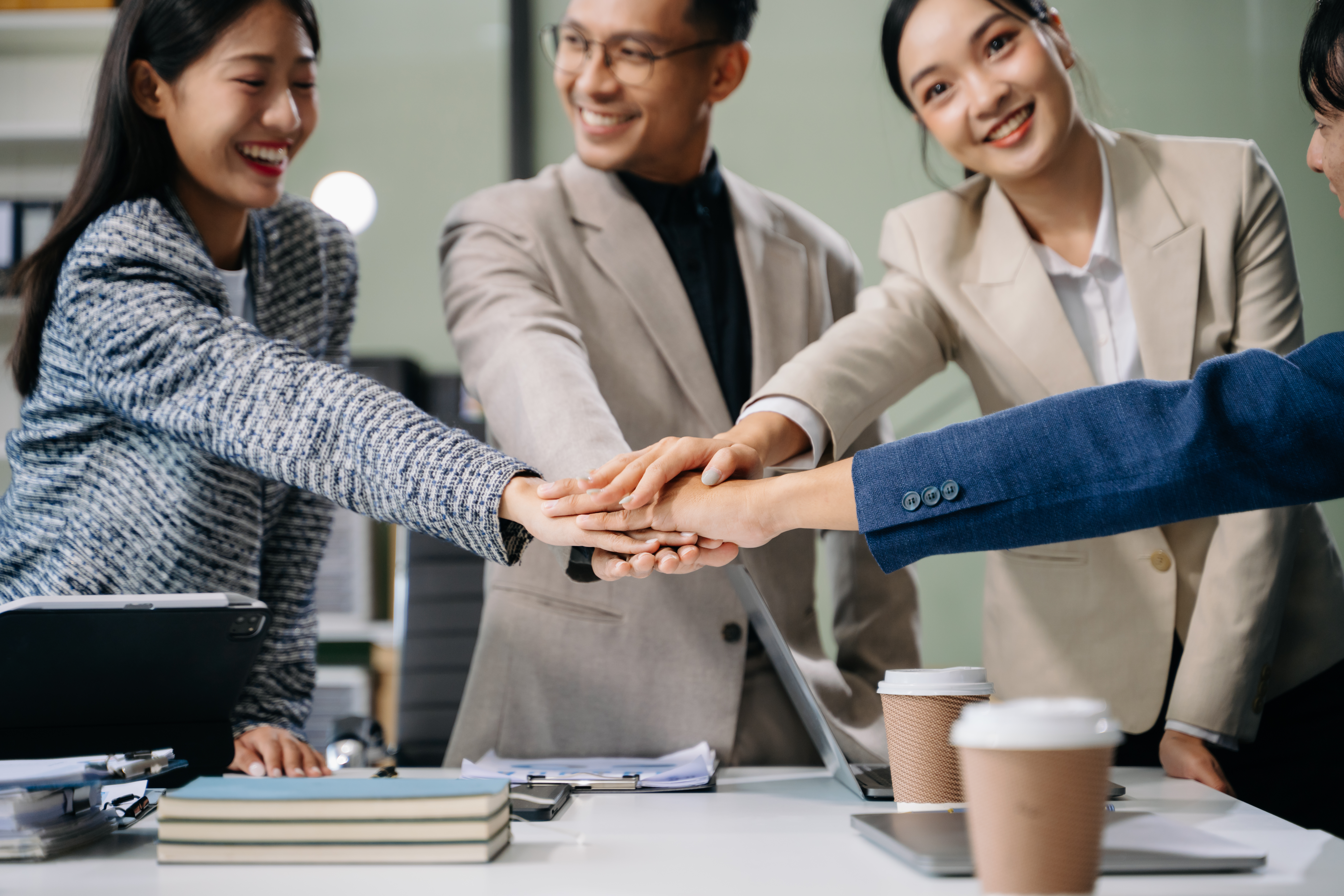 A leadership and management trainer placing their hands with colleagues